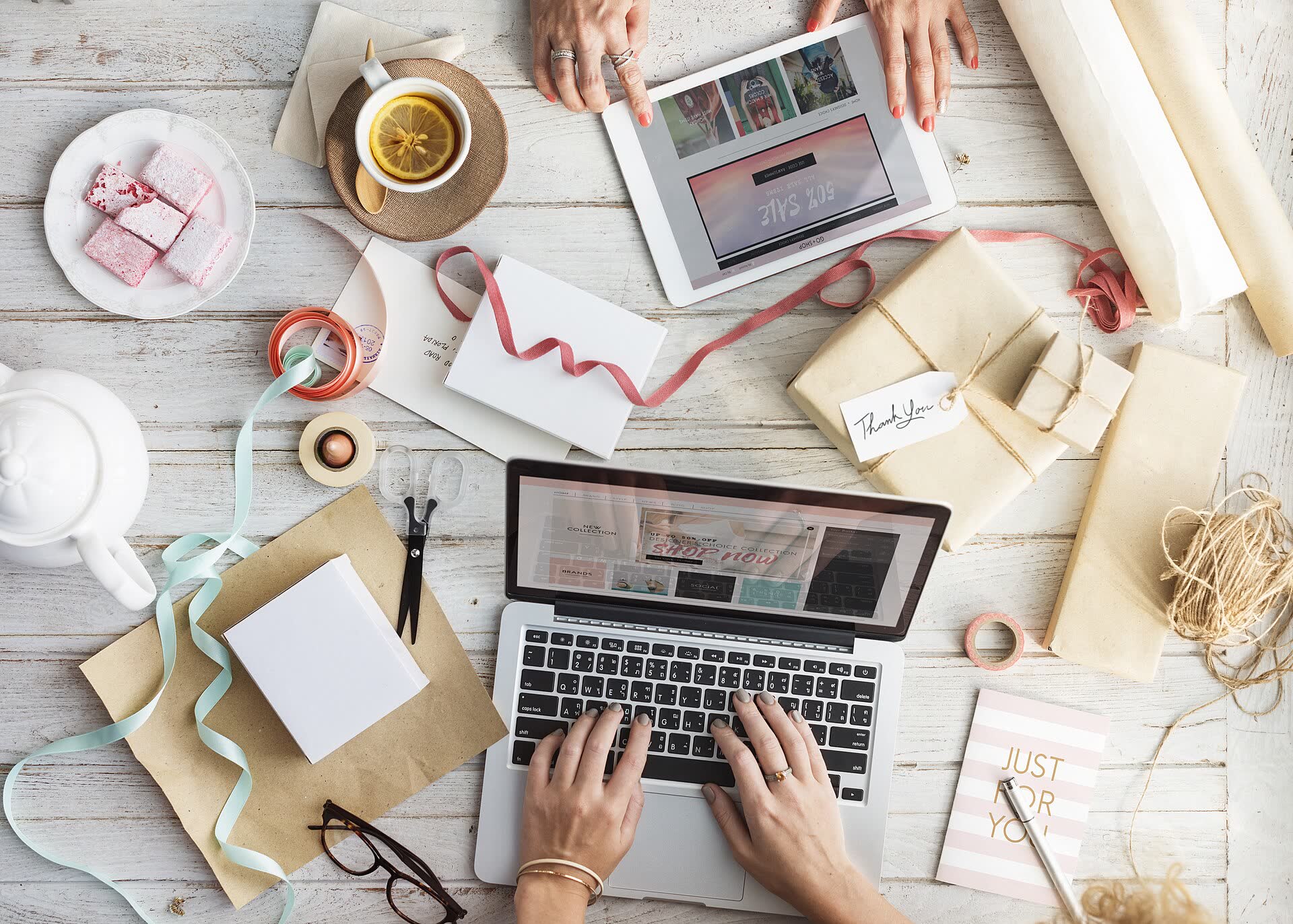 Una commerciante prepara i pacchi degli ordini online con il portatile aperto sul tavolo