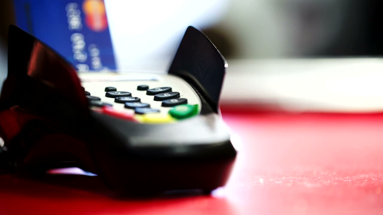Un terminale POS per le carte appoggiato accanto al registratore di cassa sul banco di un negozio